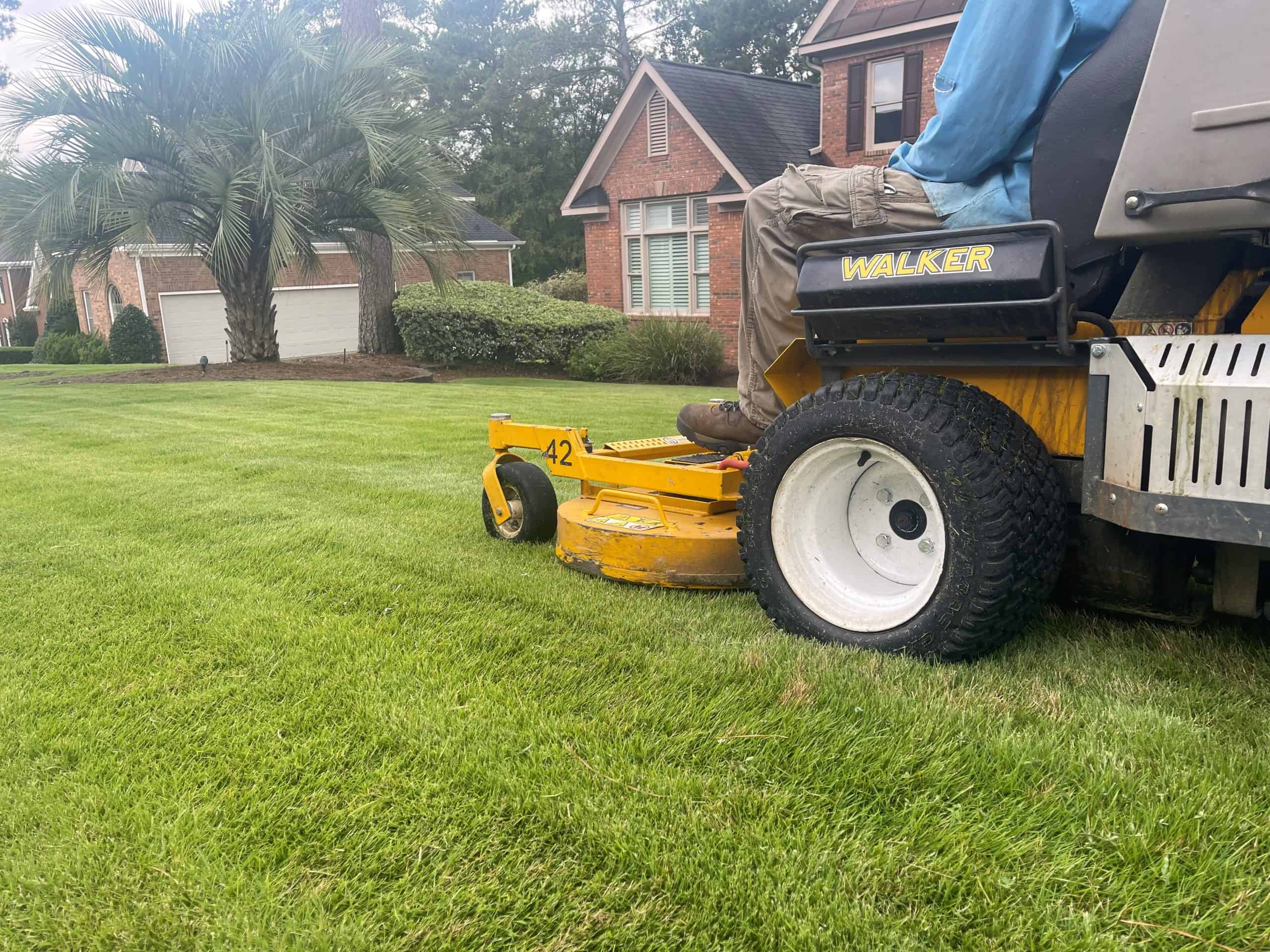 Green Lawn Augusta crew member mowing a residential lawn on a zero-turn mower in North Augusta, SC